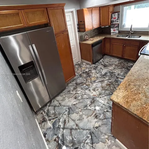 a kitchen with granite countertop a sink stove and refrigerator