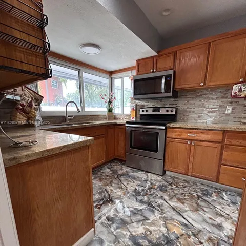 a kitchen with stainless steel appliances granite countertop a sink stove microwave and refrigerator