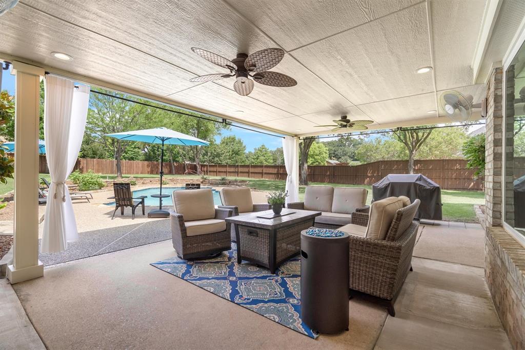 410 Simmons Road Double Oak, TX 75077 - Photo 32 of 40 Covered patio with outdoor seating overlooking the pool; made for Texas evenings.