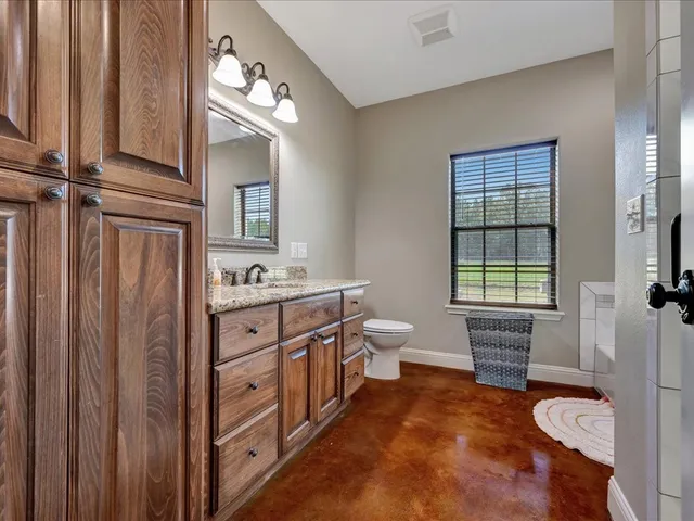 a spacious bathroom with a double vanity sink a mirror and a toilet