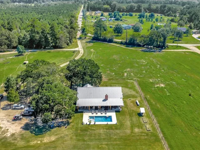 an aerial view of residential houses with outdoor space and trees