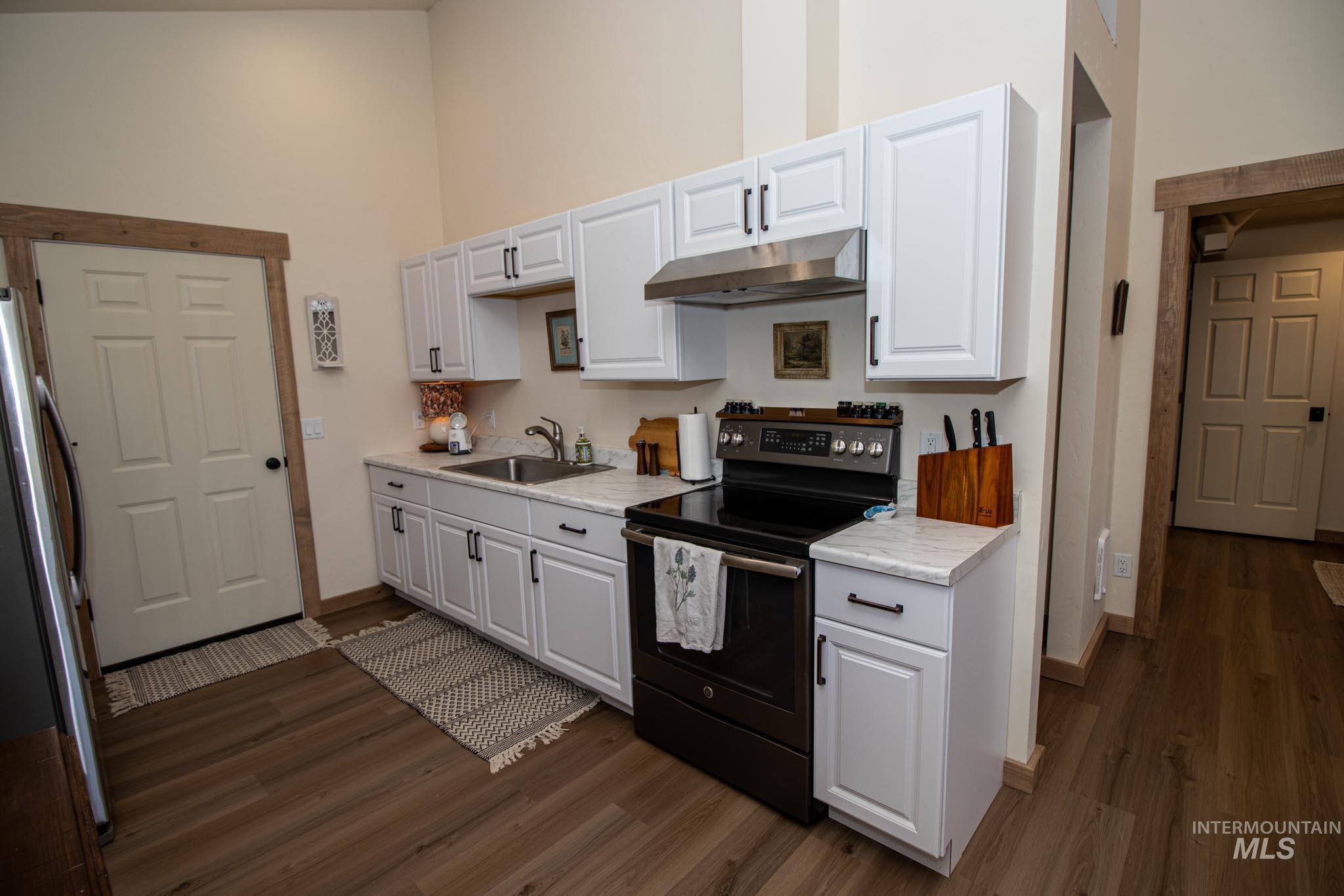 263 Glory Lane Orofino, ID 83544 - Photo 36 of 48 Kitchen with black range with electric stovetop, light countertops, freestanding refrigerator, dark wood-style floors, and a high ceiling