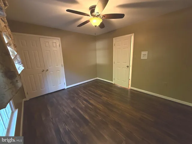 a view of a room with wooden floor and a ceiling fan