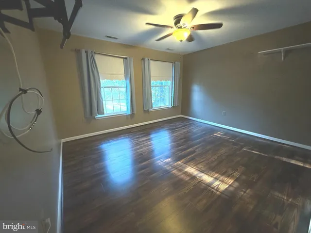 a view of an empty room with wooden floor and a bathroom