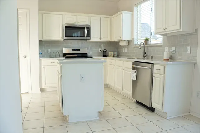 a living room with furniture and a large window with kitchen view