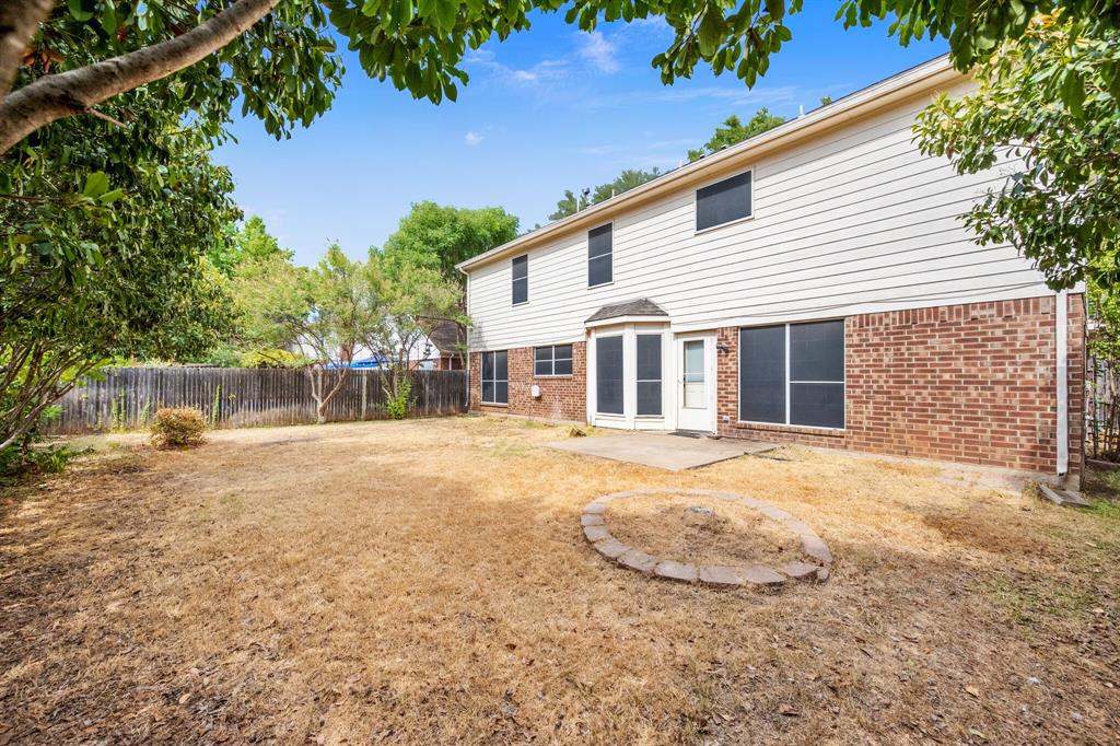 7517 Point Reyes Drive Fort Worth, TX 76137 - Photo 26 of 30 Spacious backyard featuring a defined patio area, a bay window with a door, and a stone-edged circular garden bed
