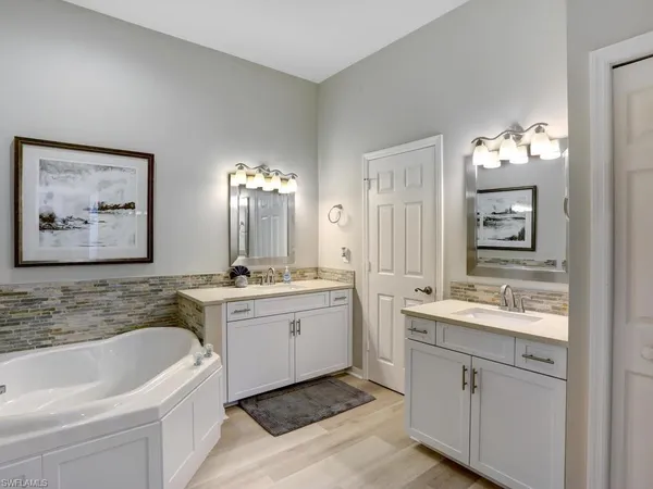 a bathroom with a double vanity sink mirror and bathtub