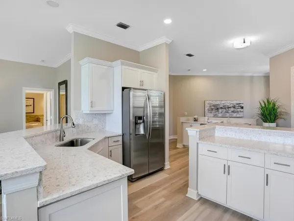 a kitchen with stainless steel appliances granite countertop a refrigerator a sink and white cabinets