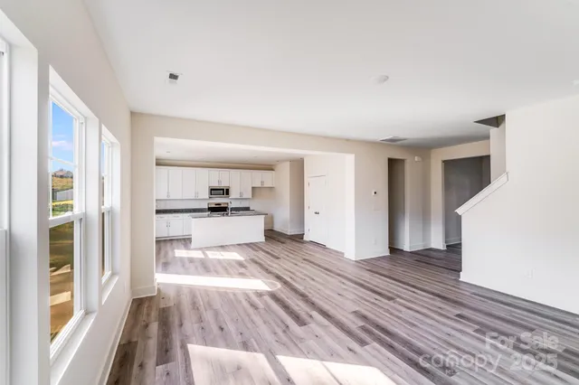 a view of a living room with wooden floor and windows