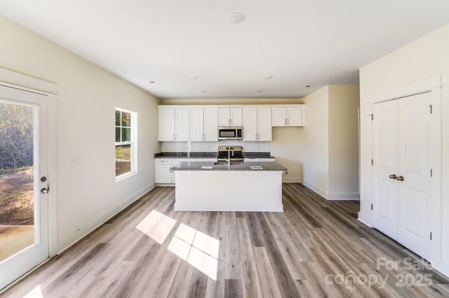 a large white kitchen with kitchen island a sink wooden floor and a window