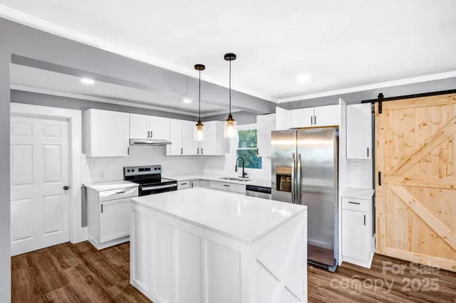 a kitchen with kitchen island granite countertop a stove a sink a center island and wooden floors