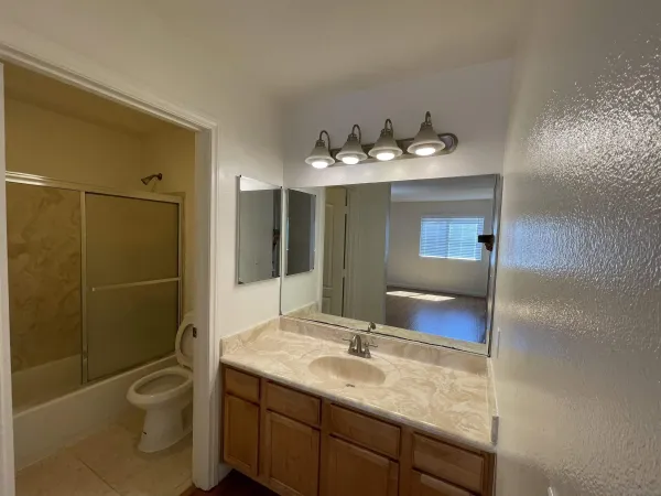a bathroom with a granite countertop sink toilet and mirror