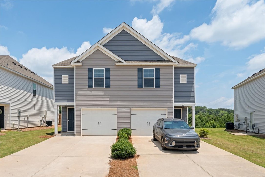 115 Adger Road Pendleton, SC 29670 - Photo 1 of 36 A contemporary duplex features a striking gray and blue facade with individual garages and ample driveway parking.
