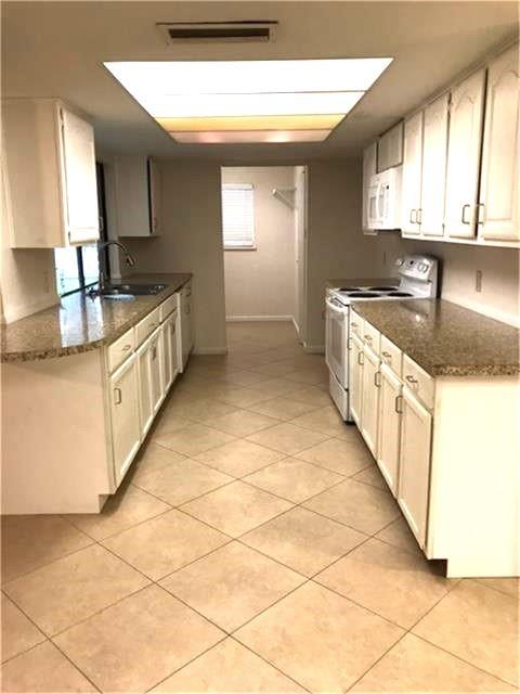 a large kitchen with granite countertop a sink a counter top space and cabinets