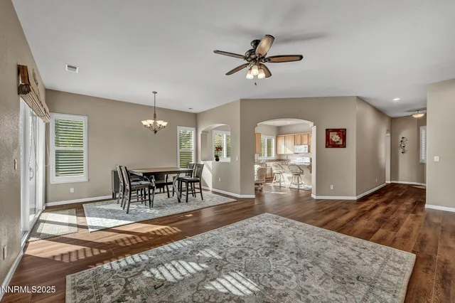 a view of a livingroom with a fireplace a ceiling fan and wooden floor