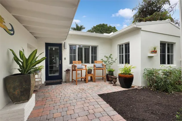a view of a patio with table and chairs potted plants and floor to ceiling window