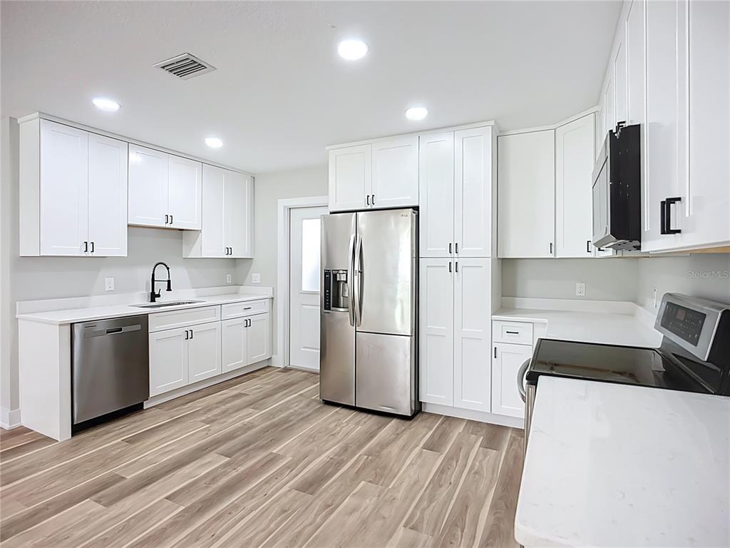 1305 Eagleview Drive Brandon, FL 33510 - Photo 9 of 27 a kitchen with a refrigerator a stove top oven and white cabinets