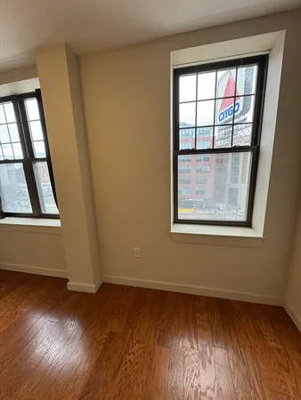an empty room with wooden floor and windows