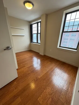 an empty room with wooden floor and windows