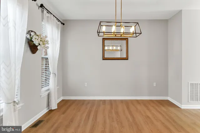 a kitchen with stainless steel appliances granite countertop a stove a sink dishwasher a refrigerator and white cabinets with wooden floor