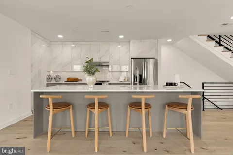 a kitchen with white cabinets and chairs