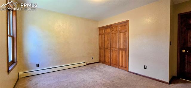 18170 Forest View Road Monument, CO 80132 - Photo 21 of 32 Unfurnished bedroom featuring a baseboard radiator, carpet, a closet, a textured wall, and baseboards