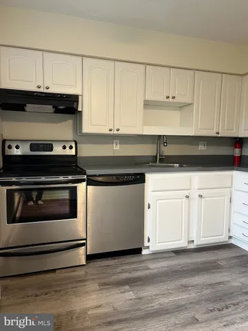 a kitchen with granite countertop white cabinets and stainless steel appliances