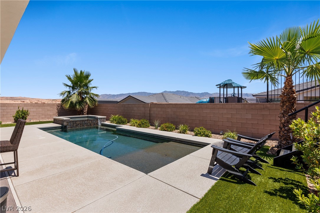 1436 Manassas Ridge Mesquite, NV 89027 - Photo 59 of 77 An inviting backyard oasis awaits, featuring a refreshing swimming pool and a tranquil spa, set against a distant mountain backdrop.