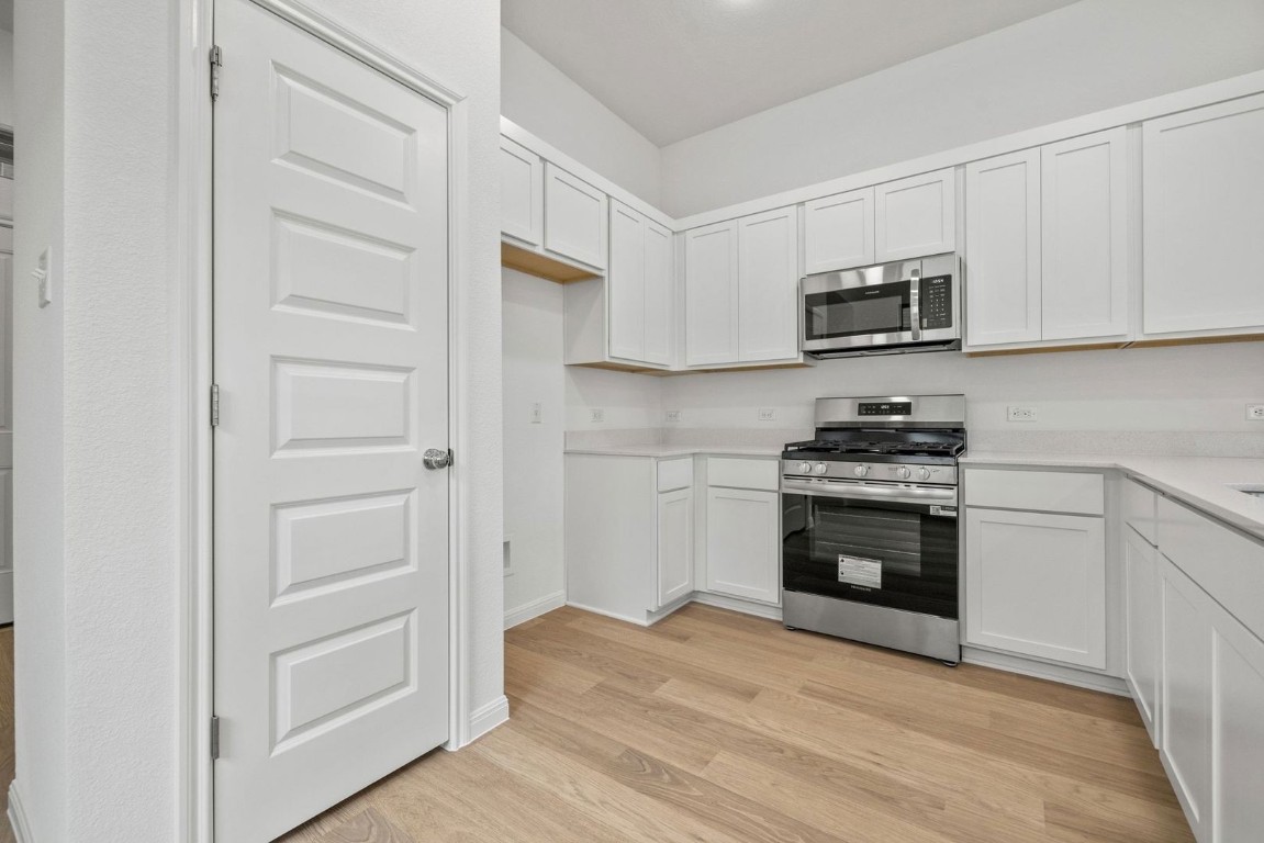 1249 Minorca Street Huffman, TX 77336 - Photo 9 of 25 a kitchen with white cabinets and stainless steel appliances