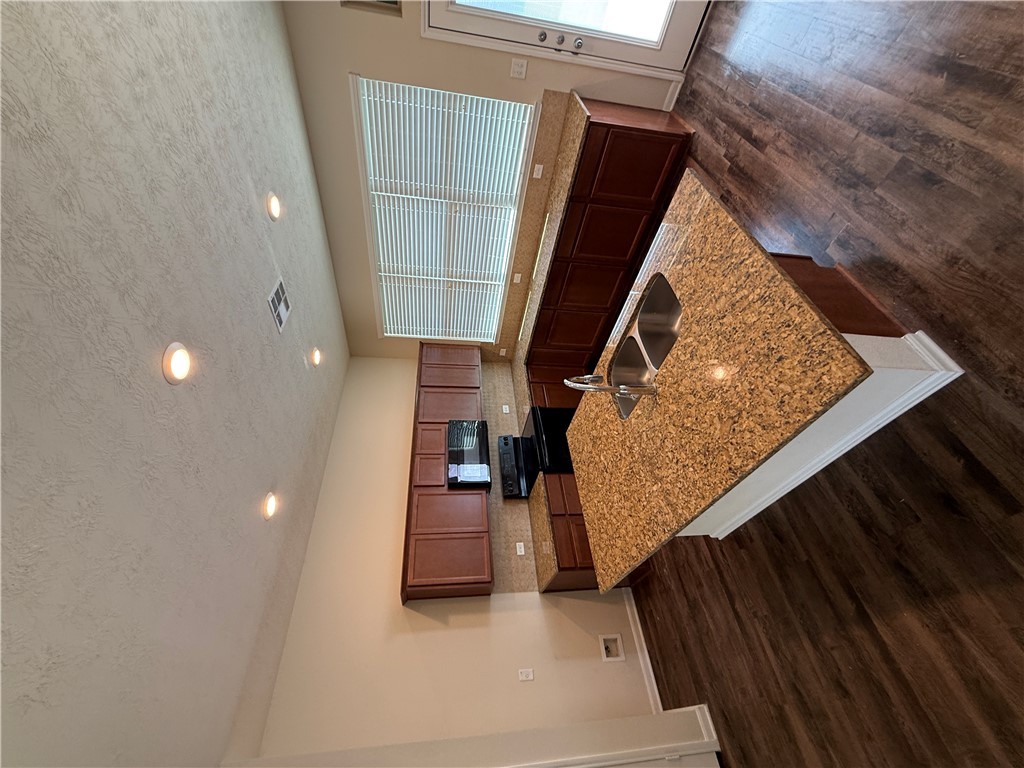 2208 Rindle Court Brenham, TX 77833 - Photo 2 of 22 a large kitchen with kitchen island a stove a counter space and wooden floor