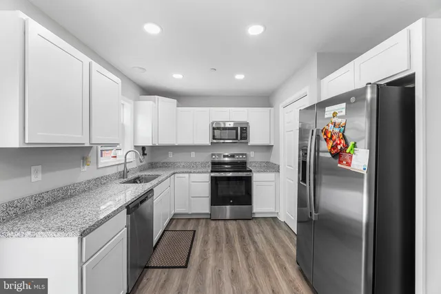 a kitchen with stainless steel appliances granite countertop a refrigerator and a stove top oven