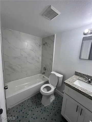 a bathroom with a granite countertop toilet a sink and a bathtub