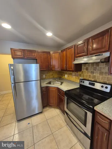 a kitchen with granite countertop a refrigerator and a stove top oven