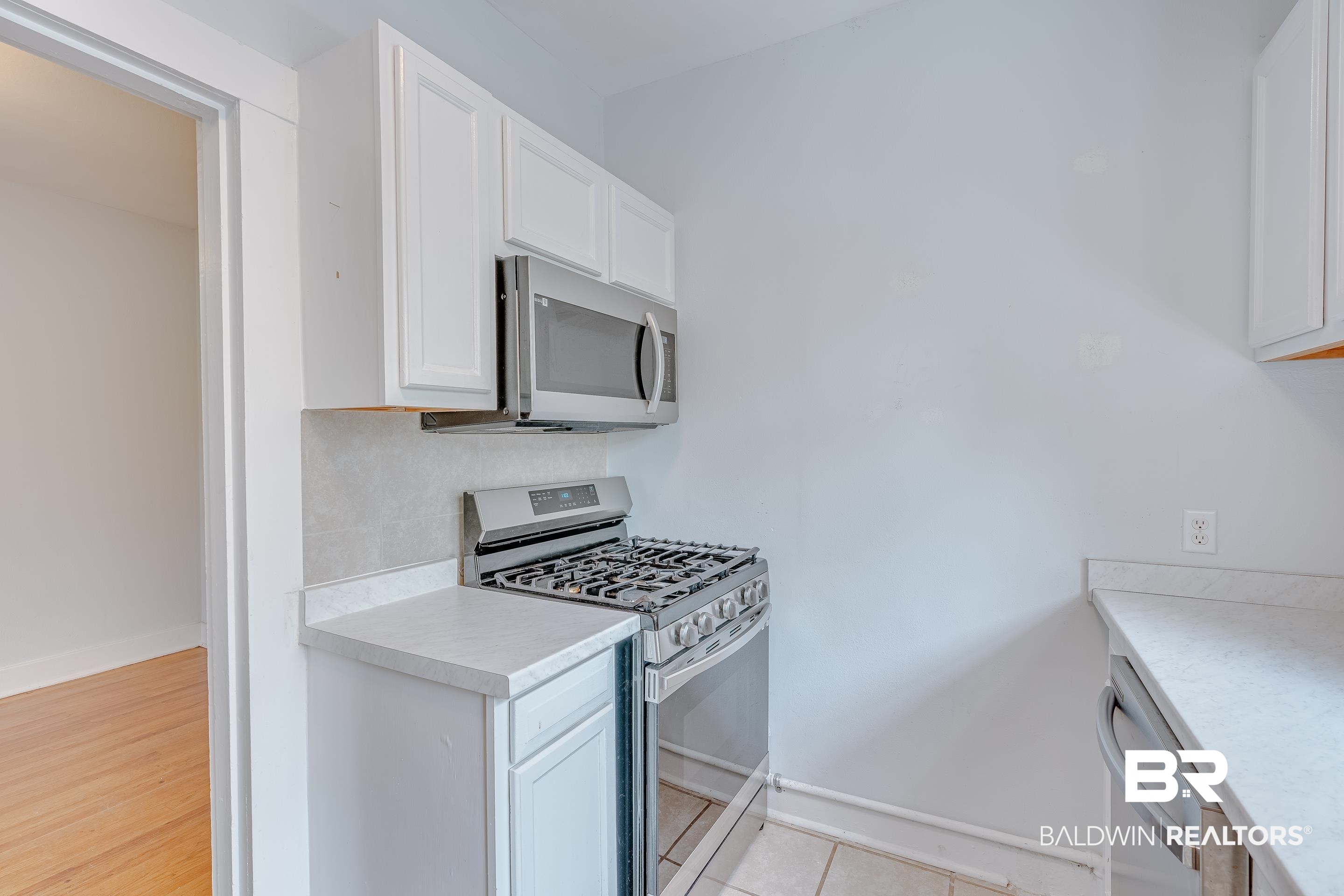 1852 Old Shell Road Mobile, AL 36607 - Photo 10 of 26 Kitchen featuring appliances with stainless steel finishes, white cabinets, light countertops, and tasteful backsplash