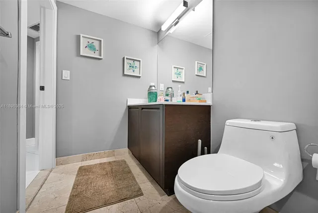 a white toilet sitting next to a bathroom sink and vanity