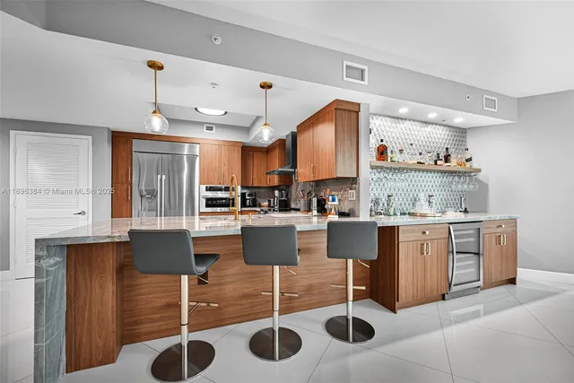 a kitchen with stainless steel appliances kitchen island granite countertop a table chairs sink and cabinets