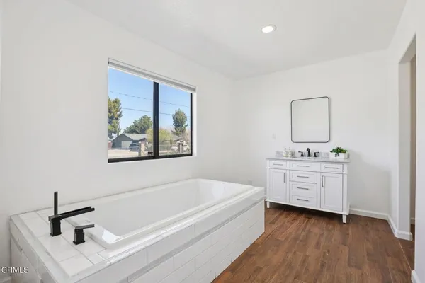 a bathroom with a bathtub sink and mirror