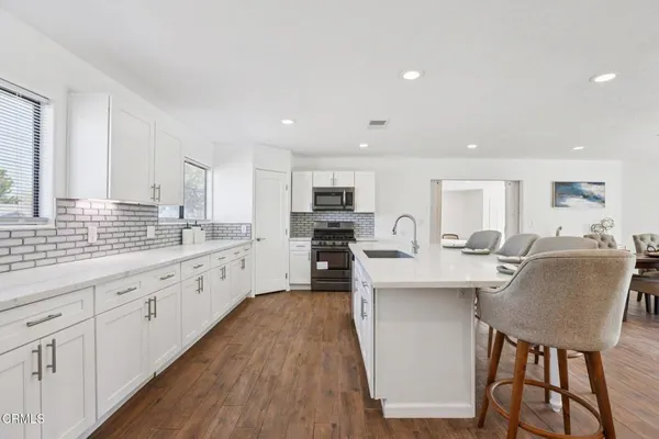 a large kitchen with cabinets a sink a window and stainless steel appliances