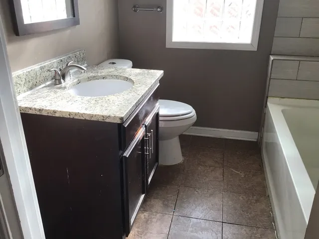 a bathroom with a granite countertop sink and a toilet