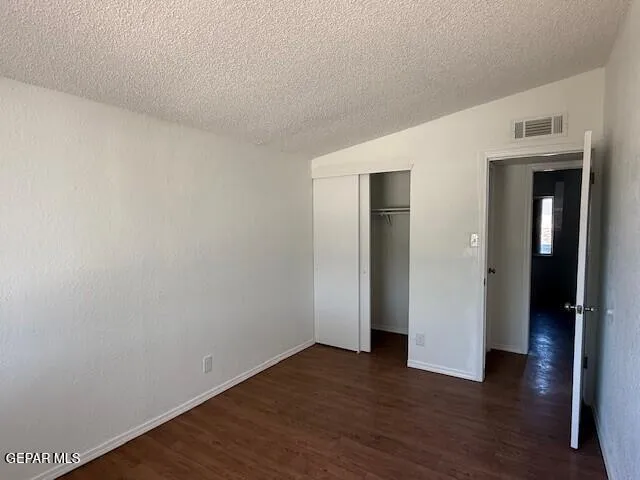 a view of an empty room with wooden floor and closet