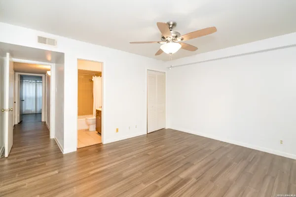 an empty room with wooden floor fan and windows