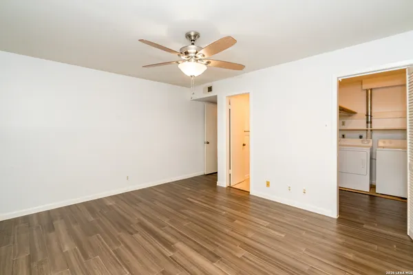 an empty room with wooden floor fan and windows