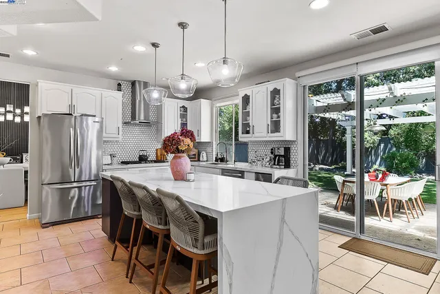 a kitchen with stainless steel appliances granite countertop a stove a refrigerator a oven a sink with a dining table and chairs