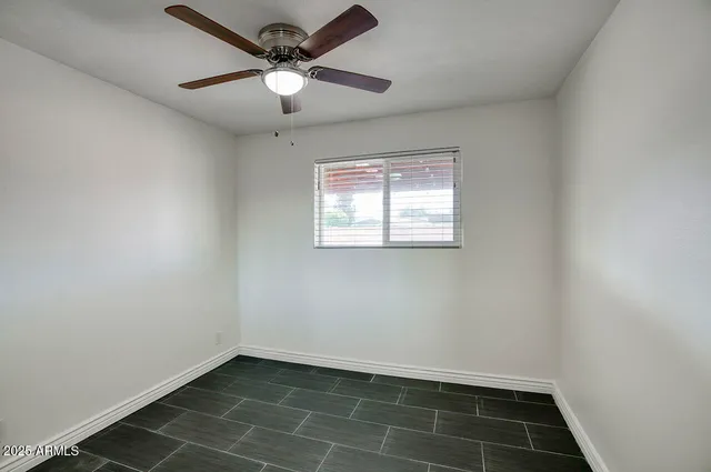 an empty room with a window and a fan