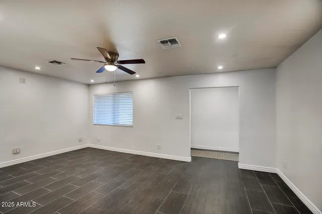 an empty room with wooden floor and a ceiling fan