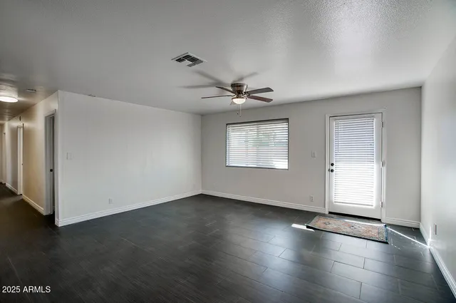 a view of an empty room with a window and wooden floor