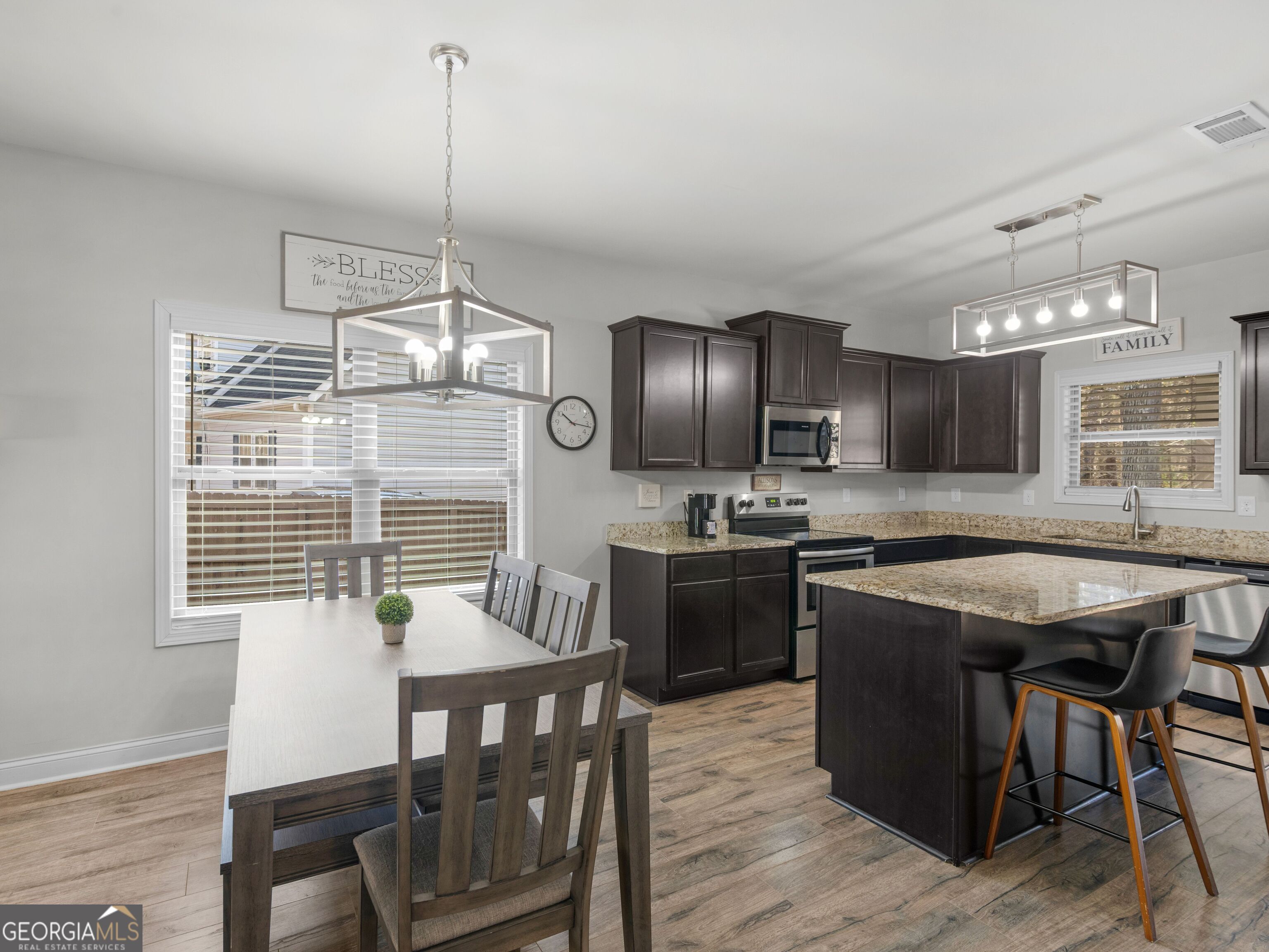 57 Partridge Court Monticello, GA 31064 - Photo 11 of 47 a kitchen with stainless steel appliances granite countertop a kitchen island hardwood floor sink stove dining table and chairs