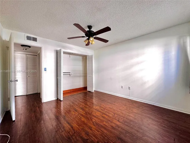 an empty room with wooden floor and a ceiling fan