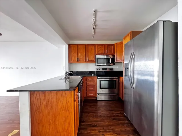 a kitchen with stainless steel appliances granite countertop a refrigerator a stove and a sink