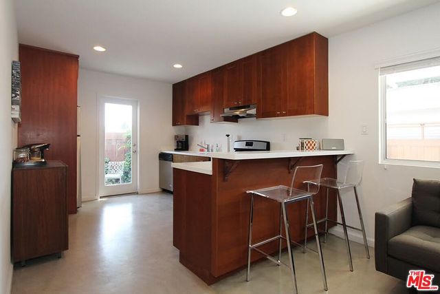 a kitchen with stainless steel appliances a sink a stove a refrigerator cabinets and a window